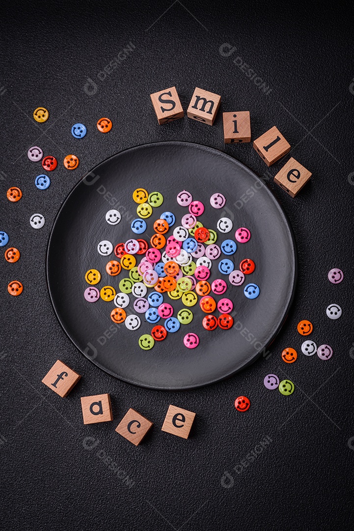 Conceito que consiste na inscrição da palavra sorriso, com emoticons redondos sobre fundo escuro de concreto. Pode ser usado como plano de fundo