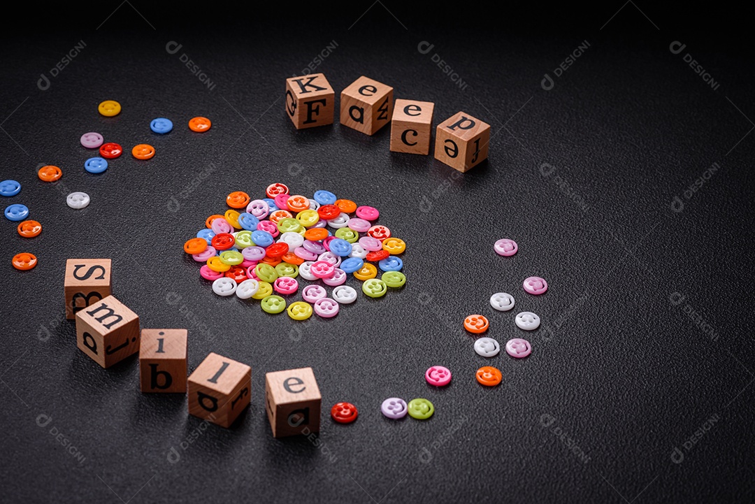 Conceito que consiste na inscrição da palavra sorriso, com emoticons redondos sobre fundo escuro de concreto. Pode ser usado como plano de fundo