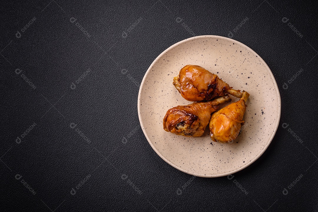 Delicioso prato asiático com pernas de frango em molho teriyaki com sal e especiarias sobre um fundo escuro de concreto