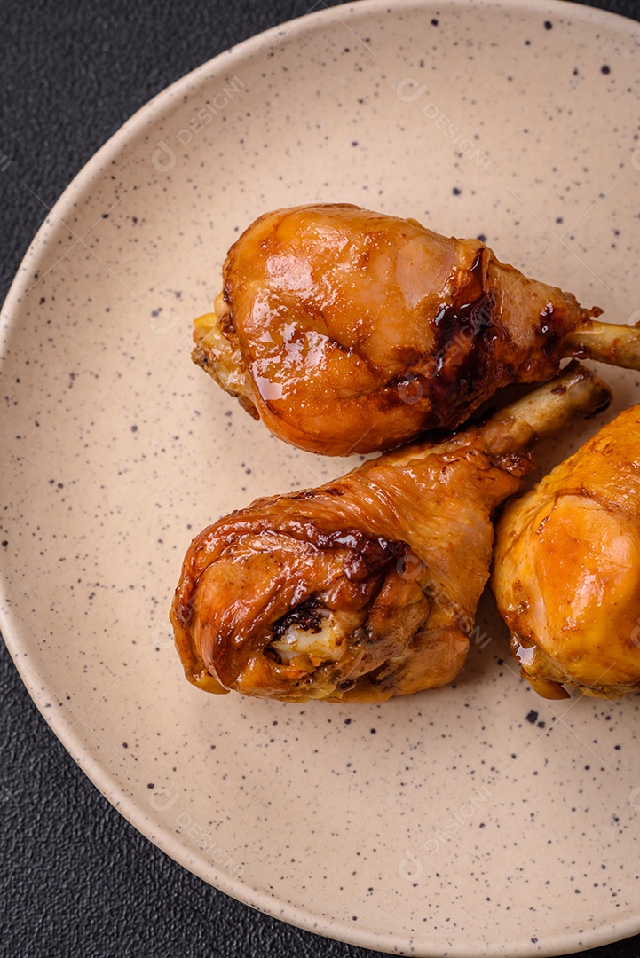 Delicioso prato asiático com pernas de frango em molho teriyaki com sal e especiarias sobre um fundo escuro de concreto