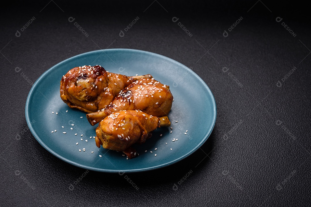 Delicioso prato asiático com pernas de frango em molho teriyaki com sal e especiarias sobre um fundo escuro de concreto