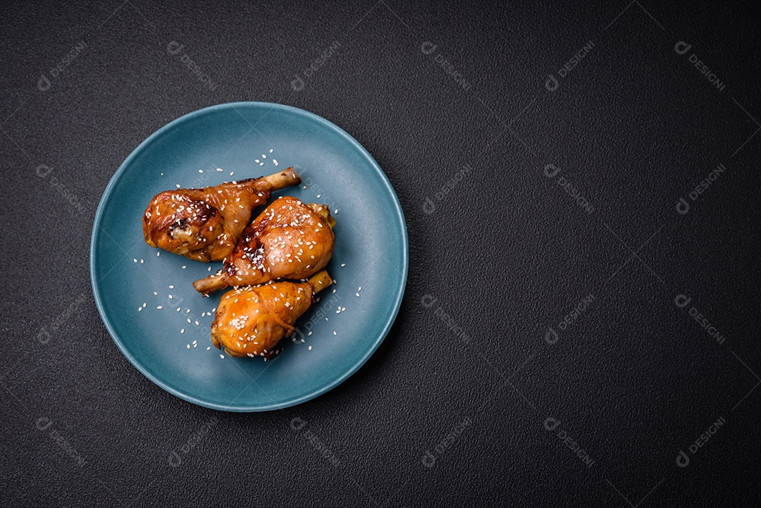 Delicioso prato asiático com pernas de frango em molho teriyaki com sal e especiarias sobre um fundo escuro de concreto