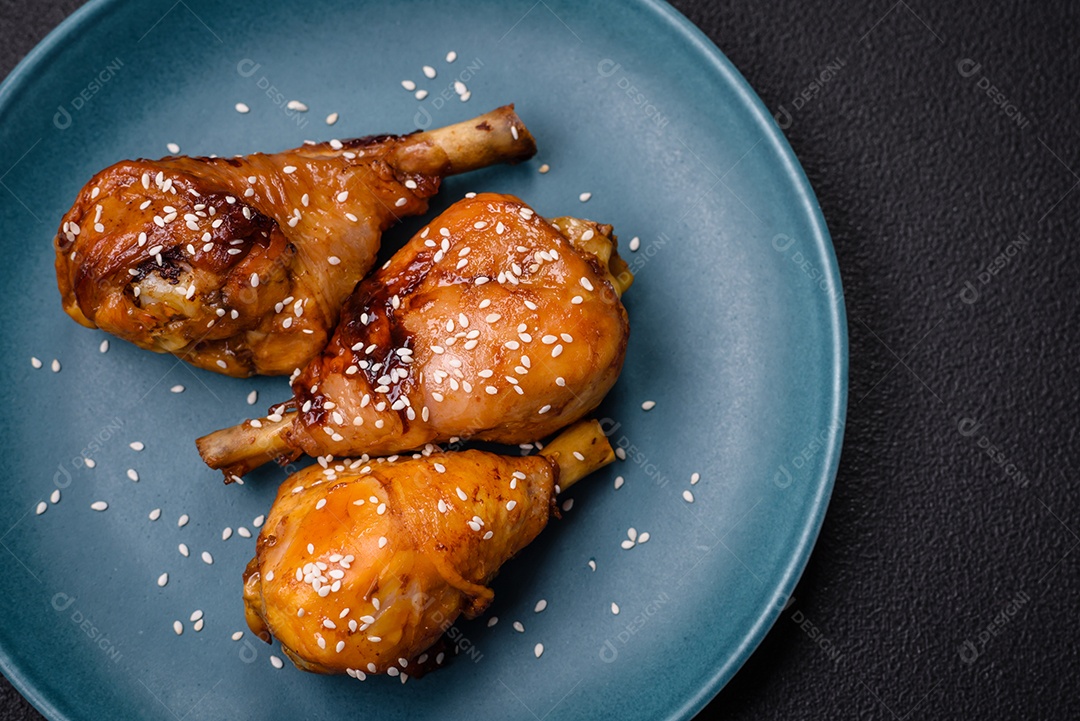 Delicioso prato asiático com pernas de frango em molho teriyaki com sal e especiarias sobre um fundo escuro de concreto