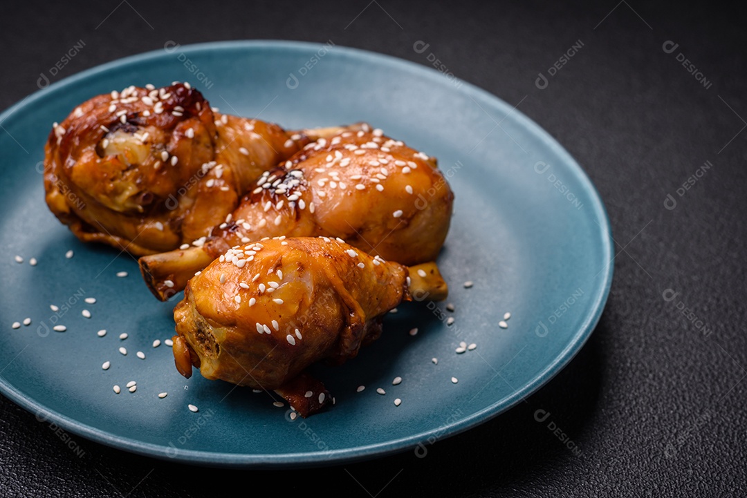 Delicioso prato asiático com pernas de frango em molho teriyaki com sal e especiarias sobre um fundo escuro de concreto