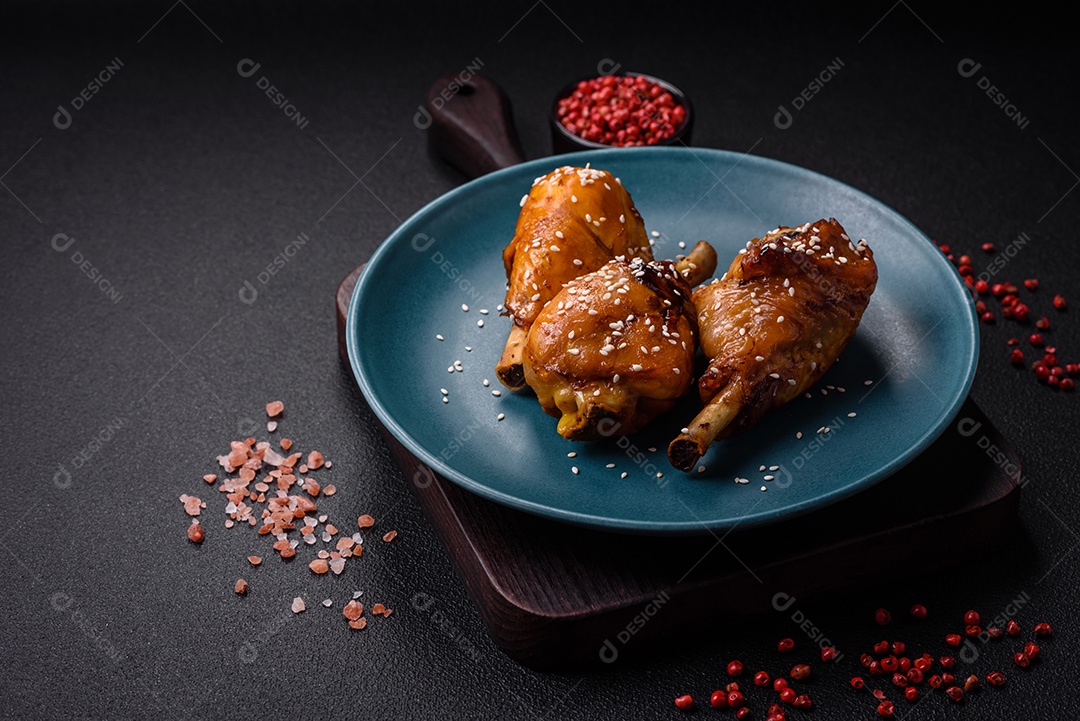 Delicioso prato asiático com pernas de frango em molho teriyaki com sal e especiarias sobre um fundo escuro de concreto