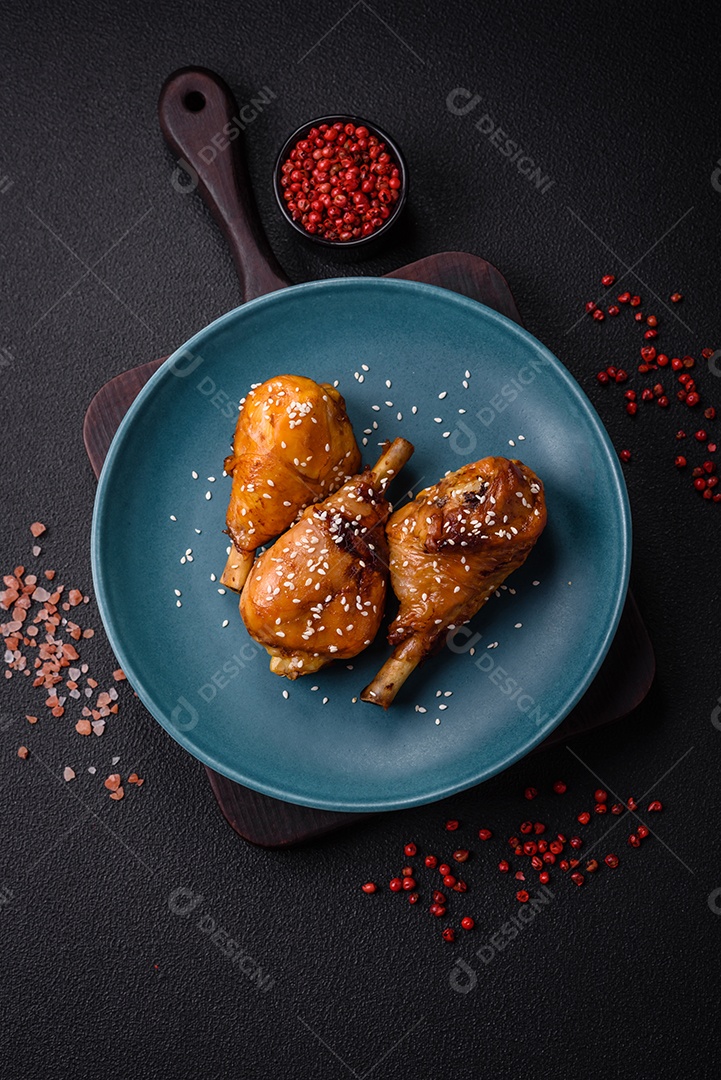 Delicioso prato asiático com pernas de frango em molho teriyaki com sal e especiarias sobre um fundo escuro de concreto