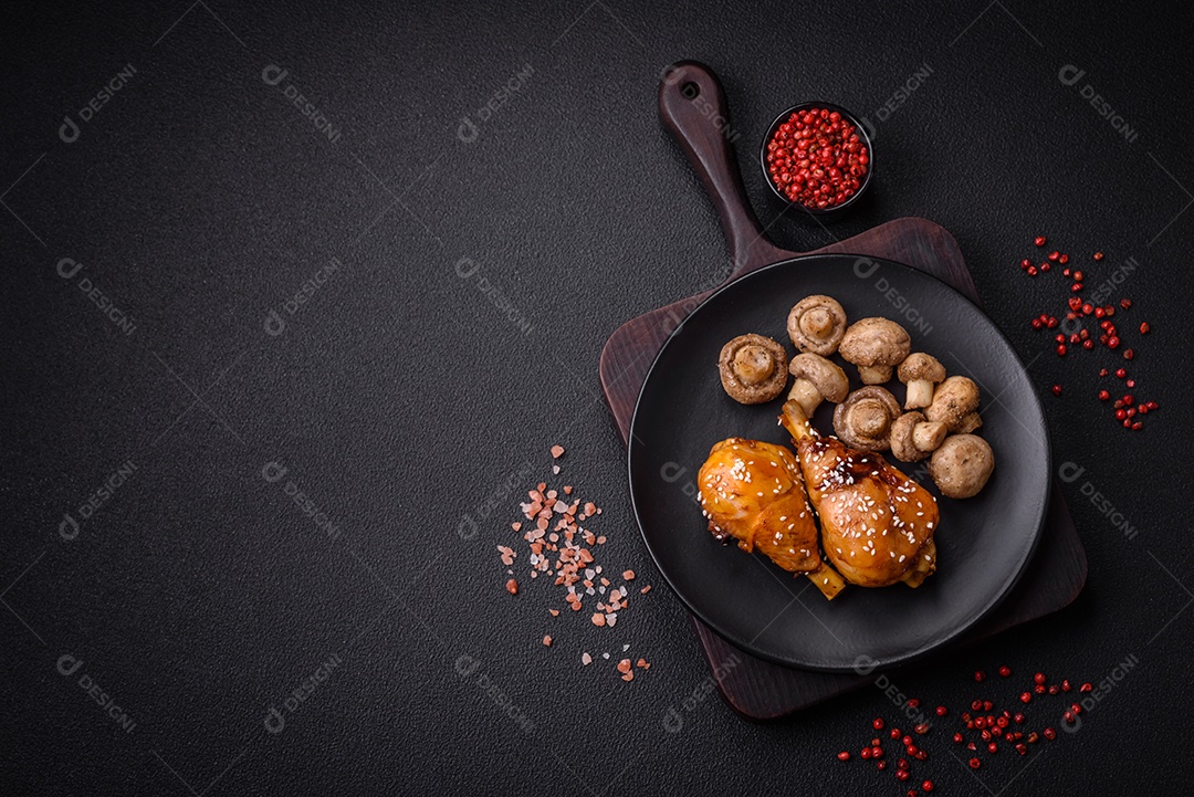 Delicioso prato asiático com pernas de frango em molho teriyaki com sal e especiarias sobre um fundo escuro de concreto