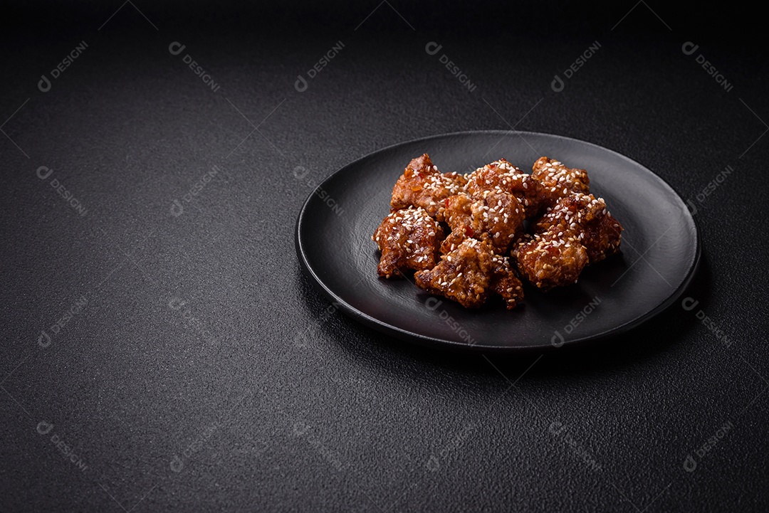 Delicioso prato asiático com pedaços de frango em molho teriyaki com sal e especiarias sobre fundo escuro de concreto