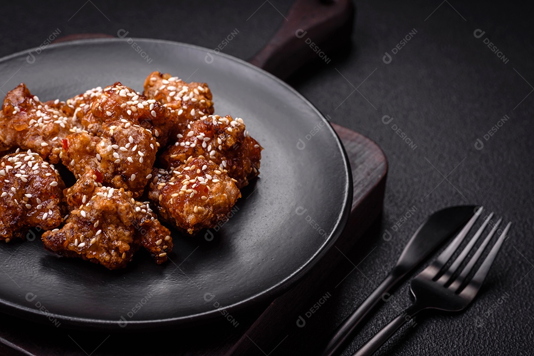 Delicioso prato asiático com pedaços de frango em molho teriyaki com sal e especiarias sobre fundo escuro de concreto