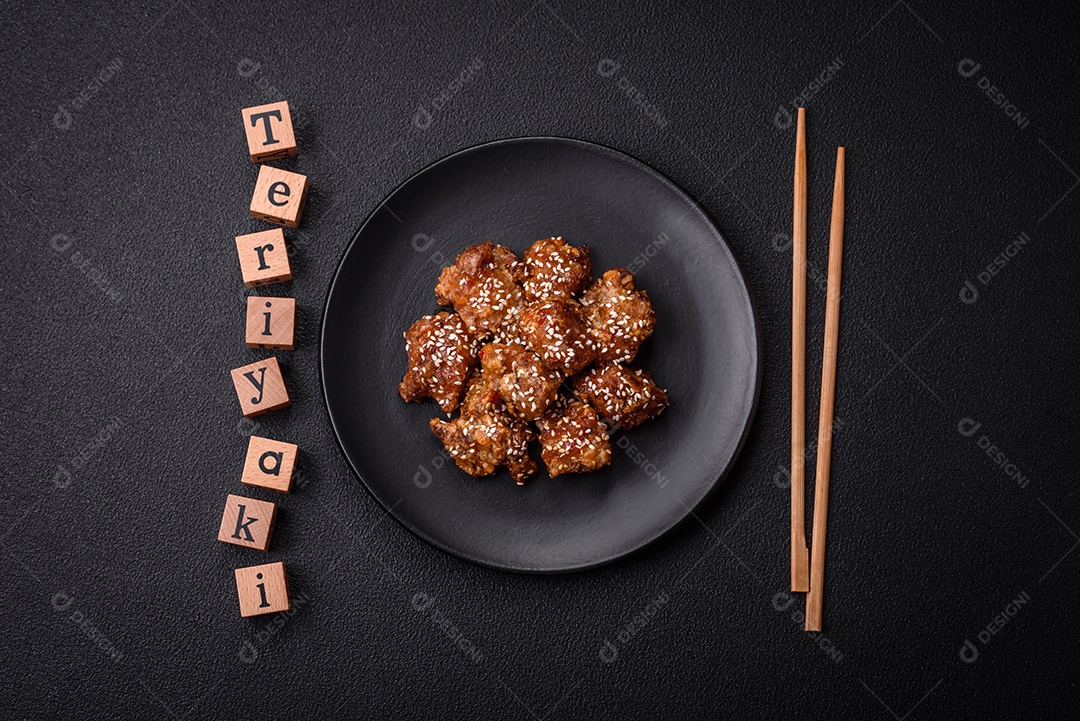 Delicioso prato asiático com pedaços de frango em molho teriyaki com sal e especiarias sobre fundo escuro de concreto
