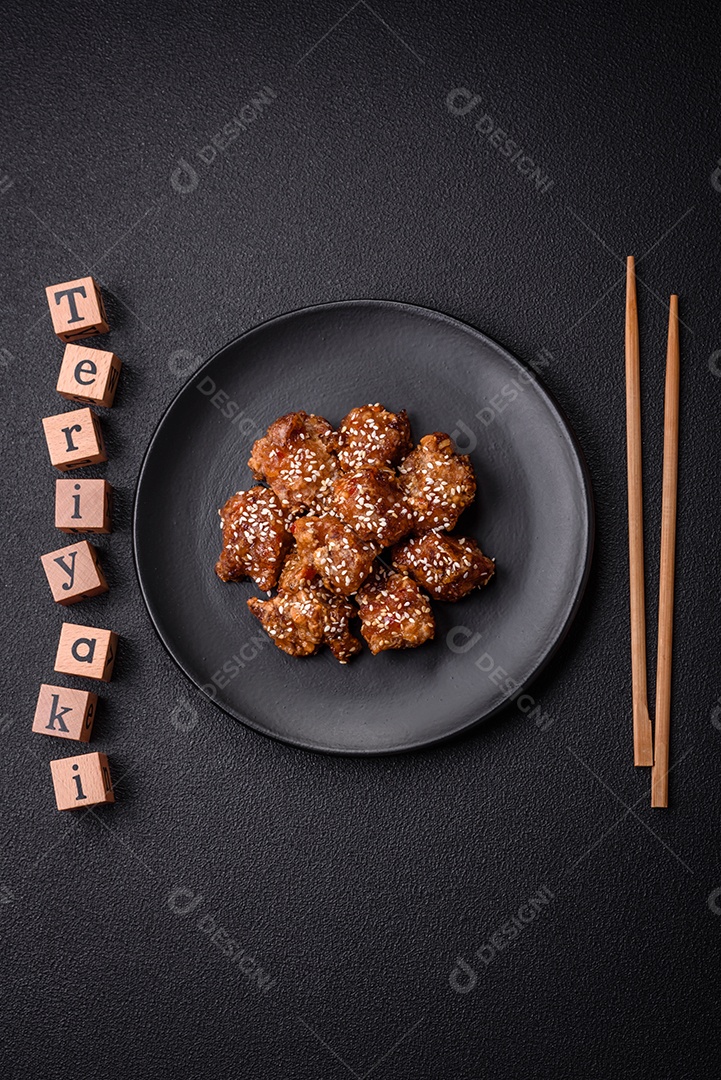 Delicioso prato asiático com pedaços de frango em molho teriyaki com sal e especiarias sobre fundo escuro de concreto