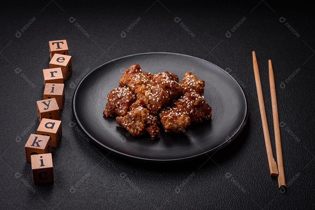 Delicioso prato asiático com pedaços de frango em molho teriyaki com sal e especiarias sobre fundo escuro de concreto