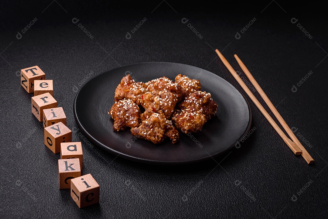 Delicioso prato asiático com pedaços de frango em molho teriyaki com sal e especiarias sobre fundo escuro de concreto