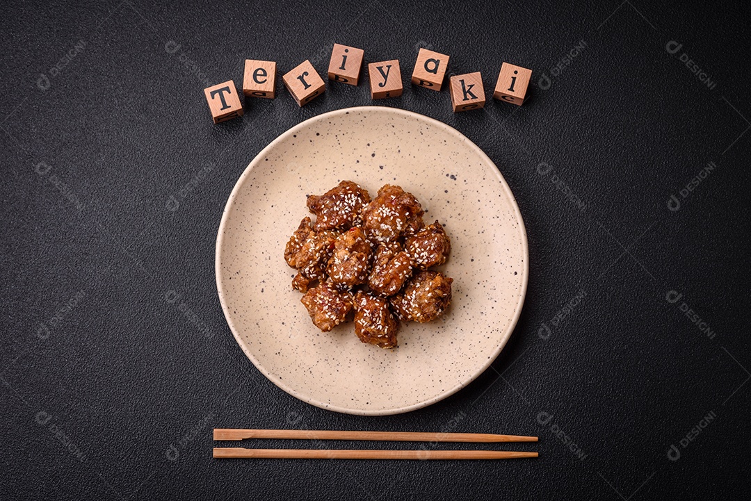 Delicioso prato asiático com pedaços de frango em molho teriyaki com sal e especiarias sobre fundo escuro de concreto