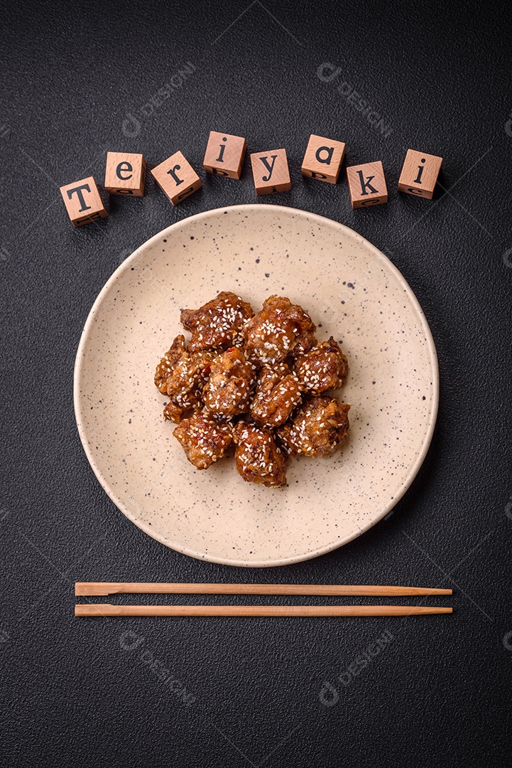Delicioso prato asiático com pedaços de frango em molho teriyaki com sal e especiarias sobre fundo escuro de concreto
