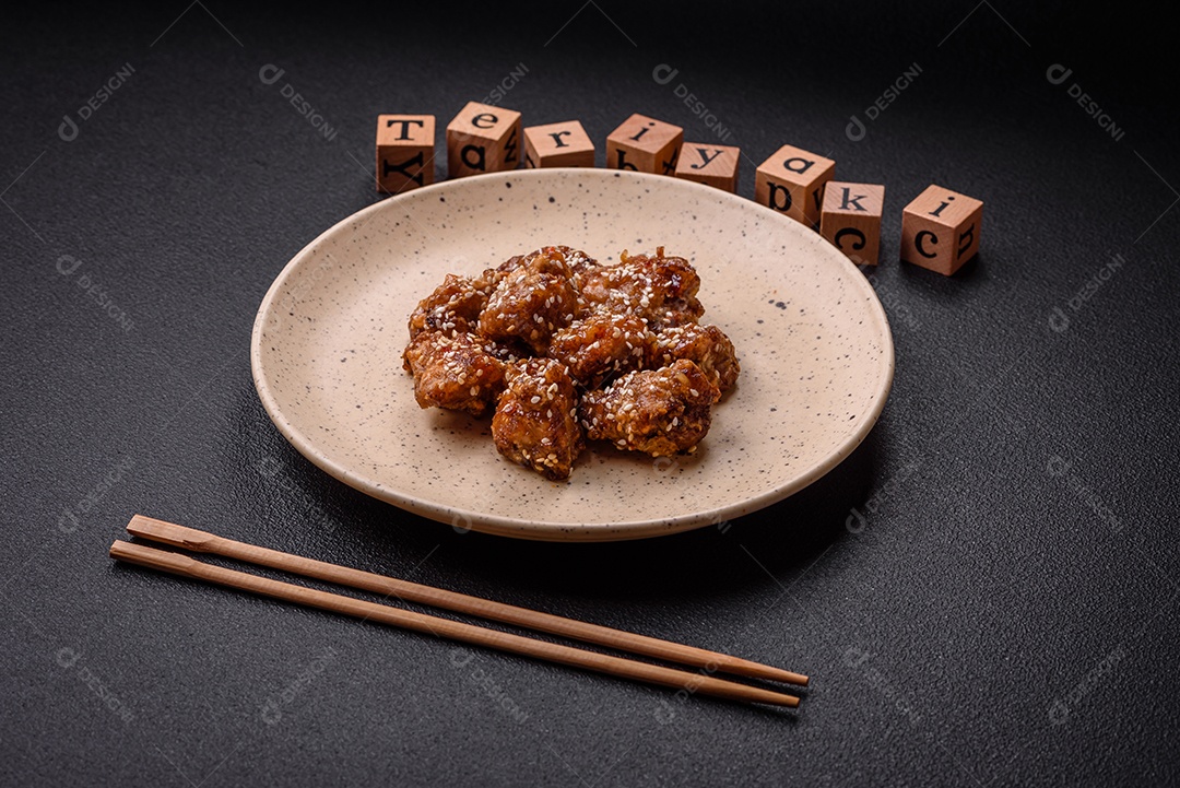 Delicioso prato asiático com pedaços de frango em molho teriyaki com sal e especiarias sobre fundo escuro de concreto