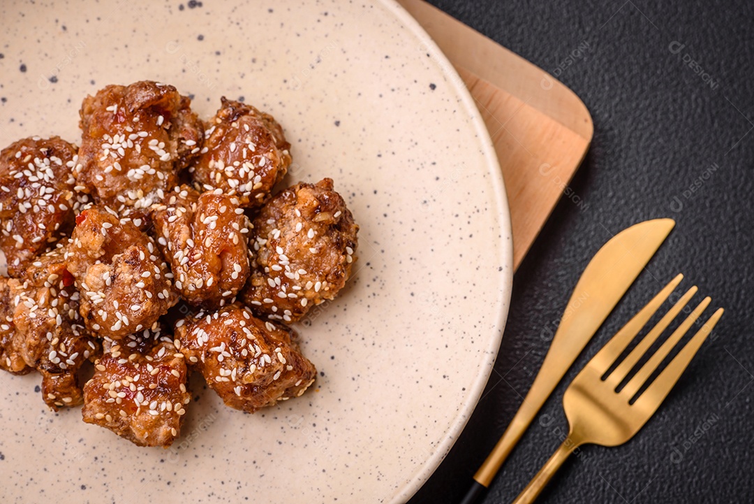 Delicioso prato asiático com pedaços de frango em molho teriyaki com sal e especiarias sobre fundo escuro de concreto