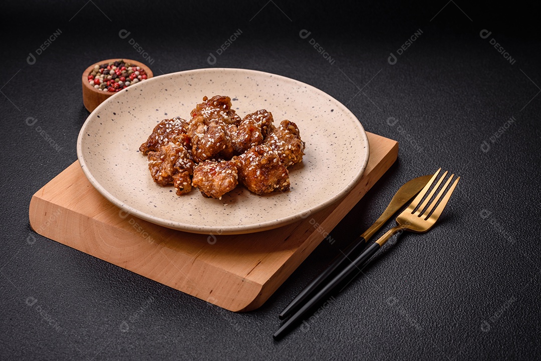 Delicioso prato asiático com pedaços de frango em molho teriyaki com sal e especiarias sobre fundo escuro de concreto