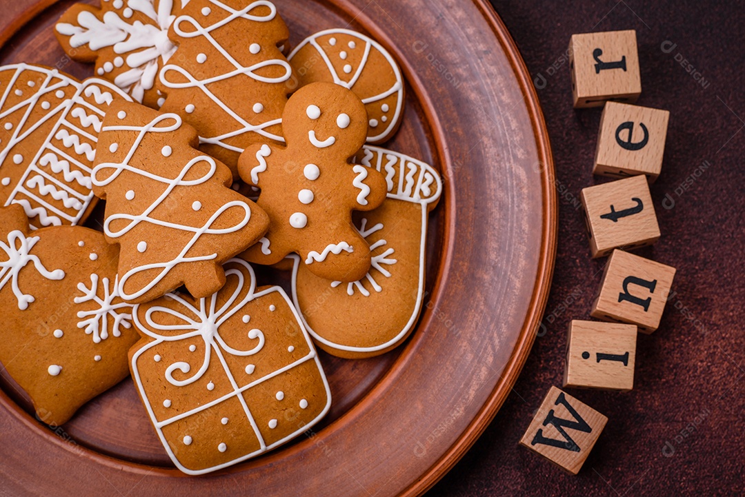 Lindos e deliciosos biscoitos de gengibre de Natal de inverno em um fundo texturizado de bronze.