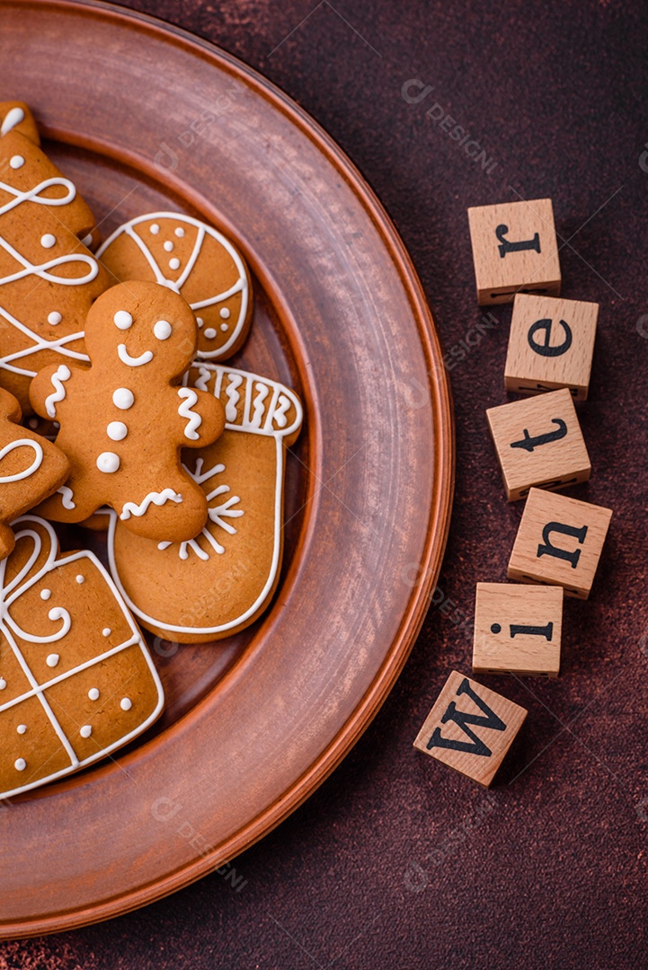 Lindos e deliciosos biscoitos de gengibre de Natal de inverno em um fundo texturizado de bronze.