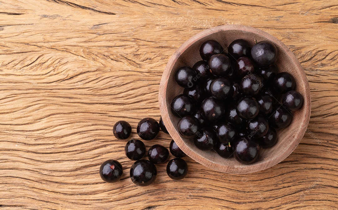 Jabuticabas em uma tigela sobre mesa de madeira com espaço de cópia.