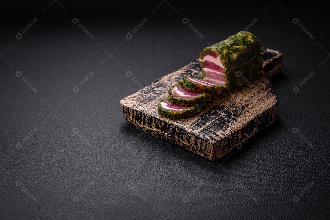 Deliciosas listras de bacon fresco com especiarias e sal sobre um fundo escuro de concreto