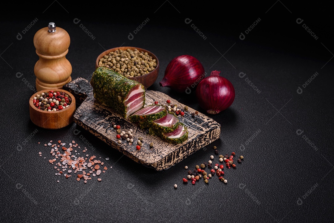 Deliciosas listras de bacon fresco com especiarias e sal sobre um fundo escuro de concreto