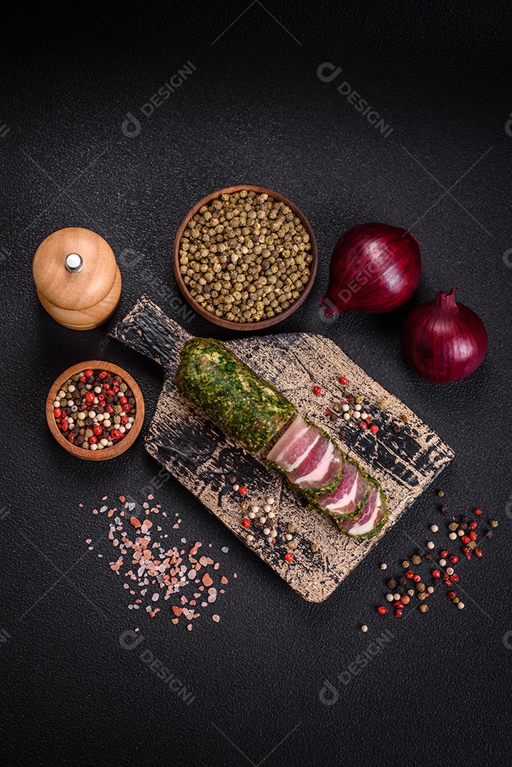 Deliciosas listras de bacon fresco com especiarias e sal sobre um fundo escuro de concreto