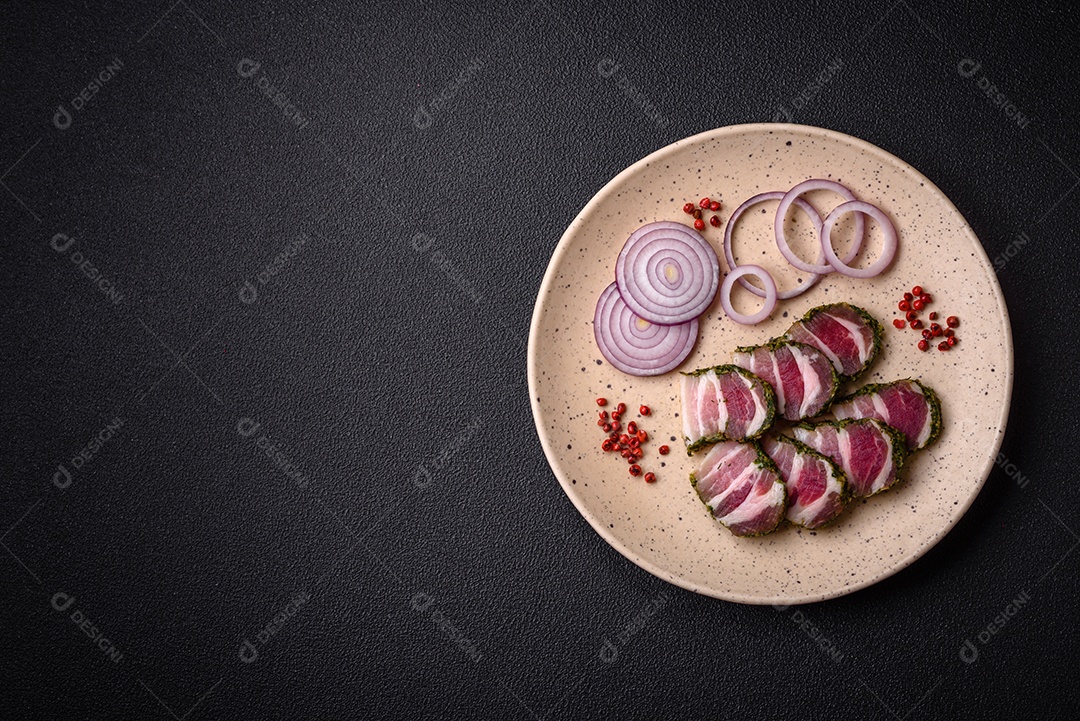 Deliciosas listras de bacon fresco com especiarias e sal sobre um fundo escuro de concreto