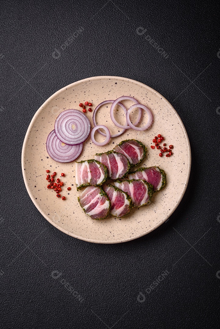 Deliciosas listras de bacon fresco com especiarias e sal sobre um fundo escuro de concreto