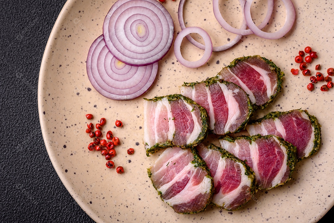 Deliciosas listras de bacon fresco com especiarias e sal sobre um fundo escuro de concreto