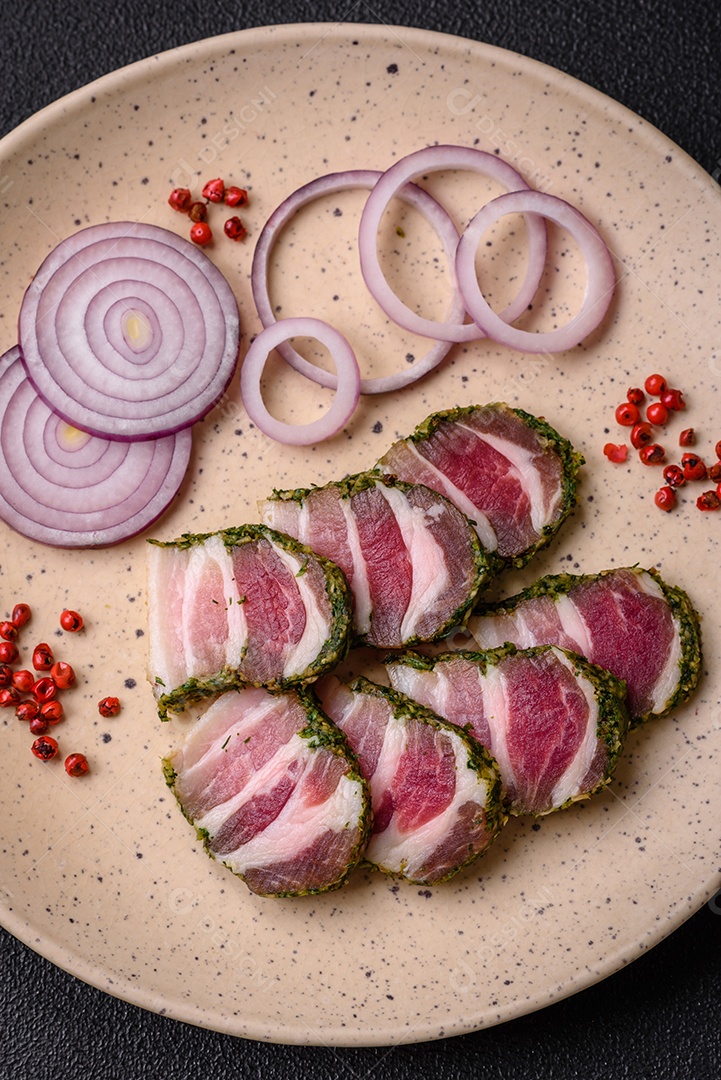 Deliciosas listras de bacon fresco com especiarias e sal sobre um fundo escuro de concreto