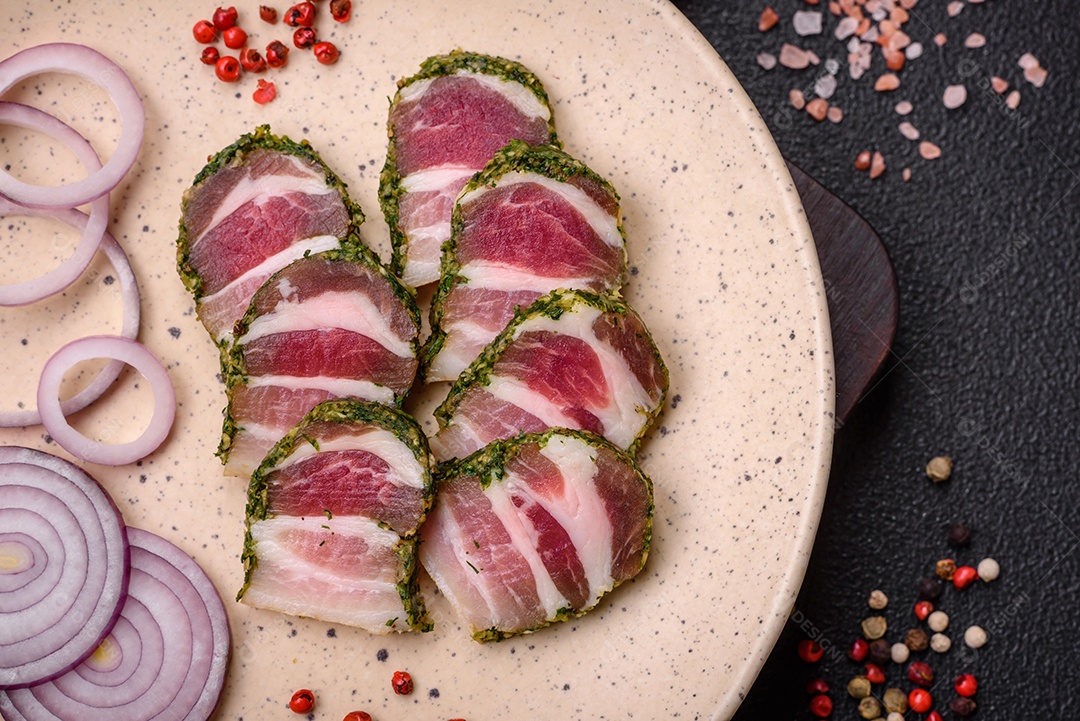 Deliciosas listras de bacon fresco com especiarias e sal sobre um fundo escuro de concreto