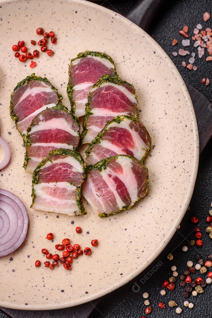 Deliciosas listras de bacon fresco com especiarias e sal sobre um fundo escuro de concreto