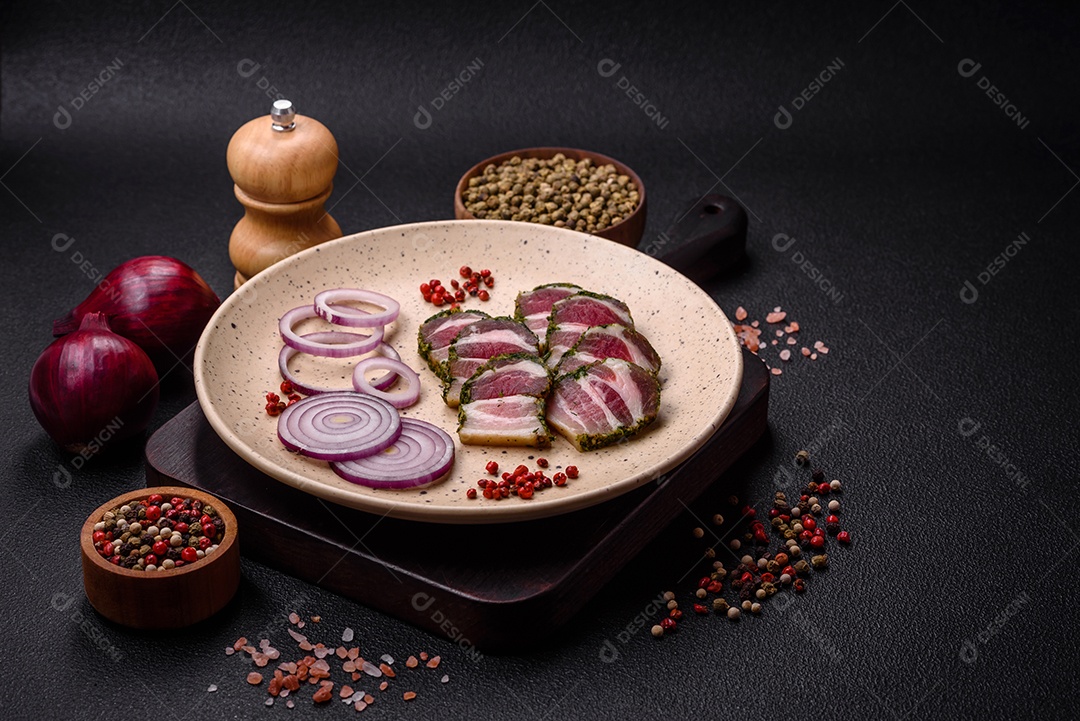 Deliciosas listras de bacon fresco com especiarias e sal sobre um fundo escuro de concreto