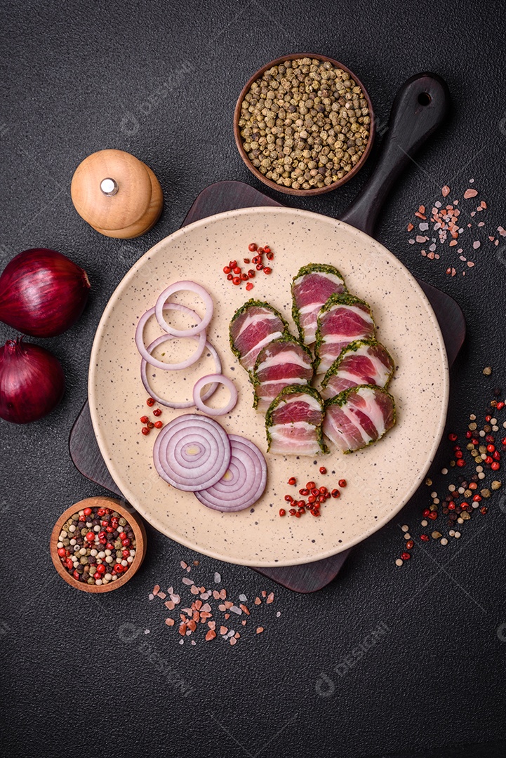 Deliciosas listras de bacon fresco com especiarias e sal sobre um fundo escuro de concreto