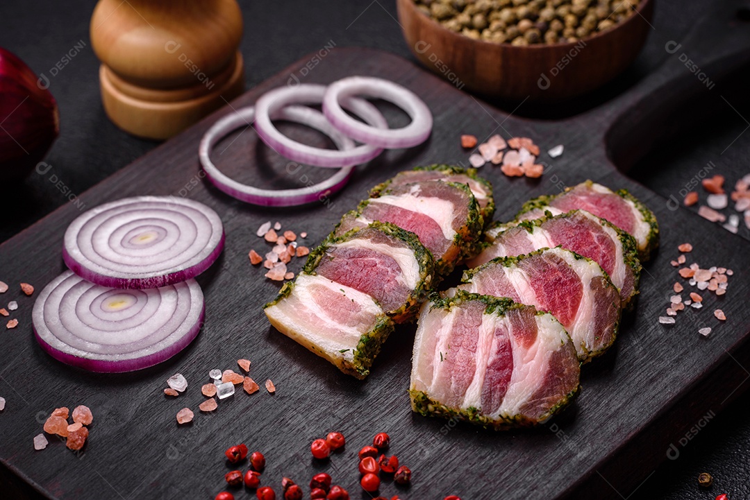 Deliciosas listras de bacon fresco com especiarias e sal sobre um fundo escuro de concreto