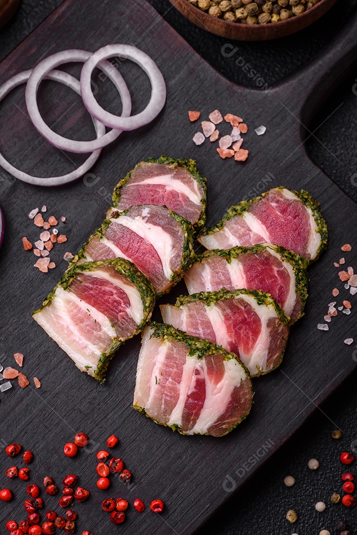 Deliciosas listras de bacon fresco com especiarias e sal sobre um fundo escuro de concreto