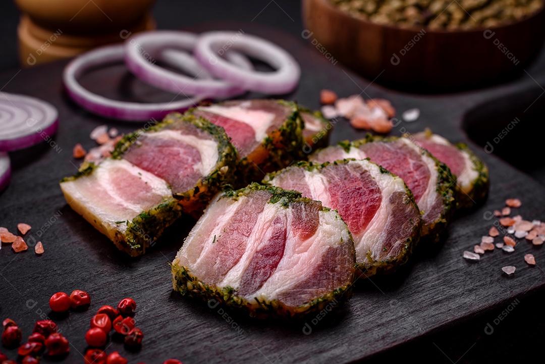 Deliciosas listras de bacon fresco com especiarias e sal sobre um fundo escuro de concreto