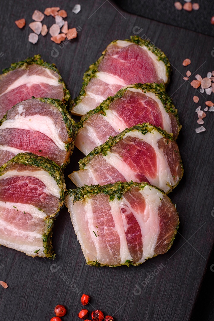 Deliciosas listras de bacon fresco com especiarias e sal sobre um fundo escuro de concreto