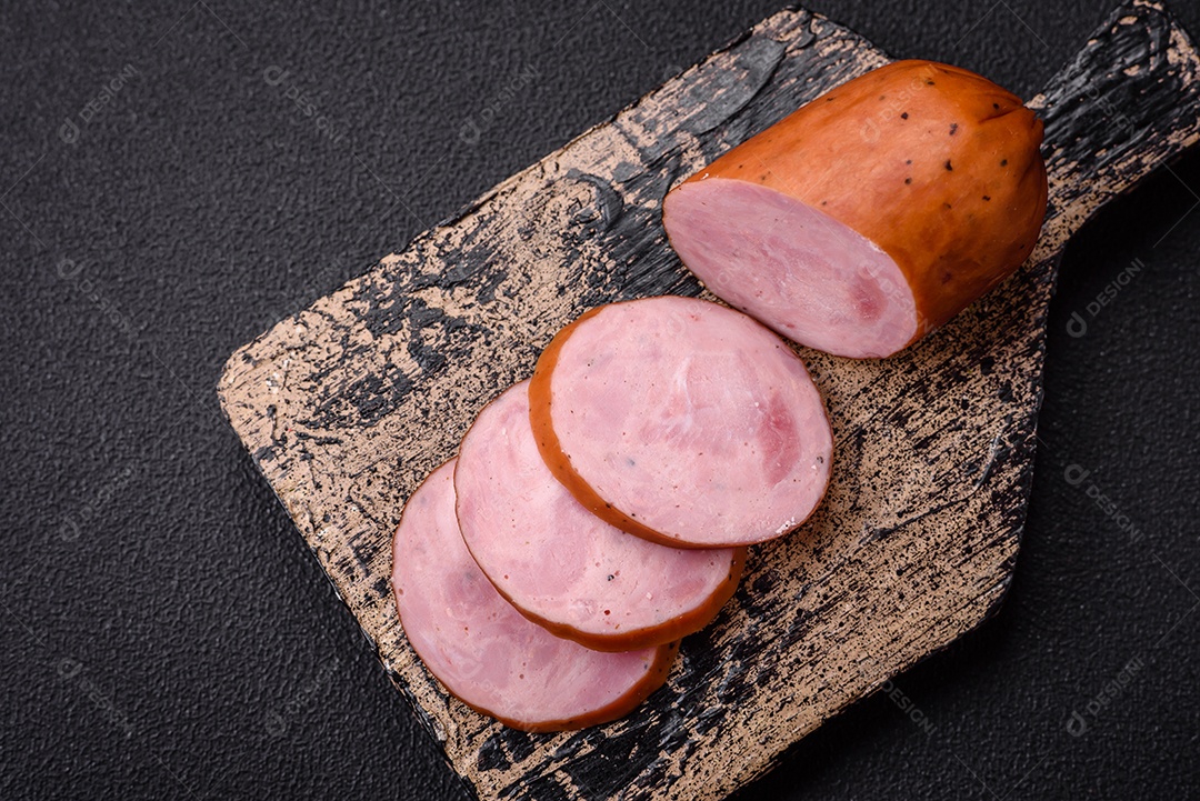 Deliciosa salsicha defumada com sal e especiarias cortadas em fatias sobre um fundo escuro de concreto
