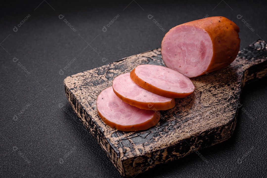 Deliciosa salsicha defumada com sal e especiarias cortadas em fatias sobre um fundo escuro de concreto
