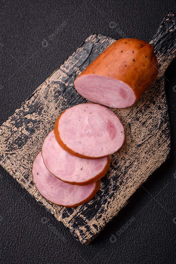 Deliciosa salsicha defumada com sal e especiarias cortadas em fatias sobre um fundo escuro de concreto