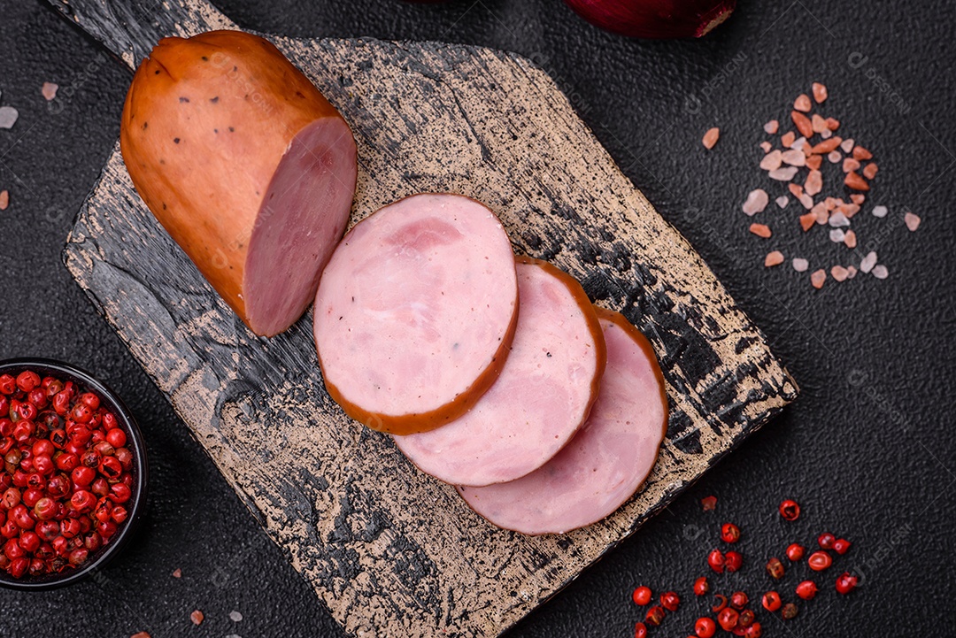 Deliciosa salsicha defumada com sal e especiarias cortadas em fatias sobre um fundo escuro de concreto
