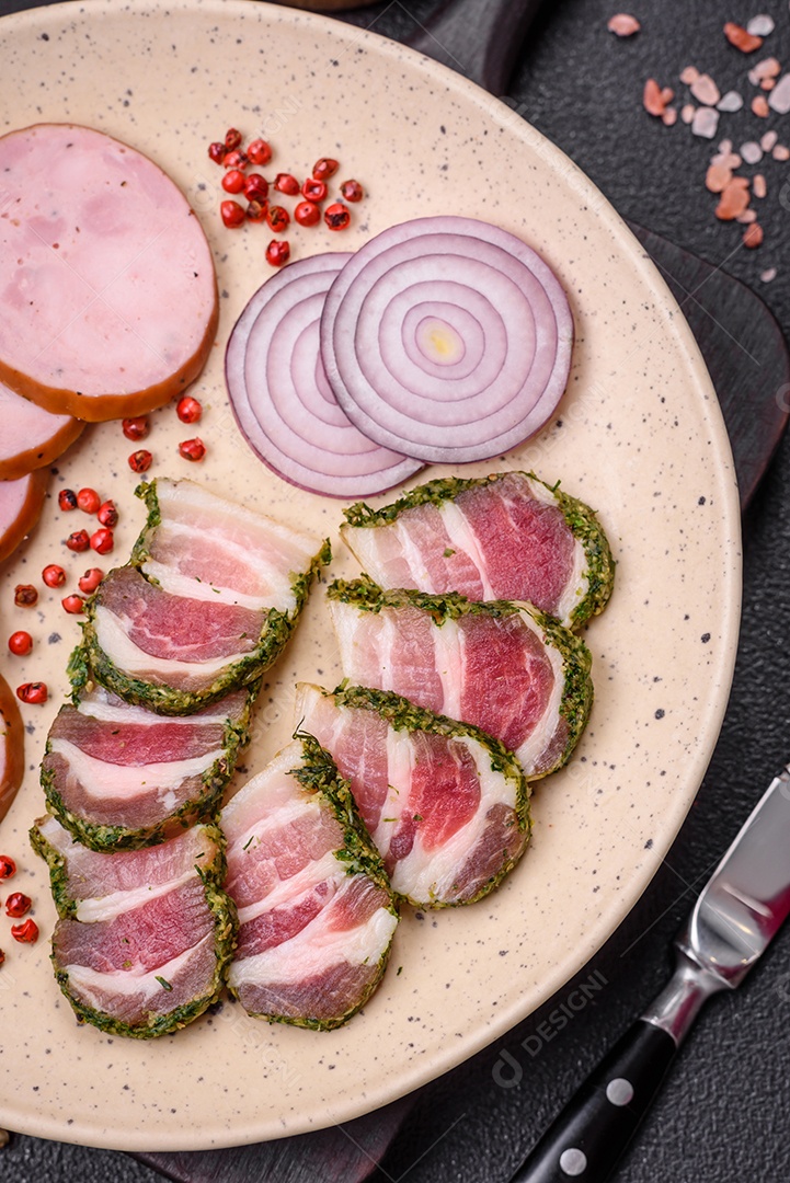 Deliciosas listras de bacon fresco com especiarias e sal sobre um fundo escuro de concreto