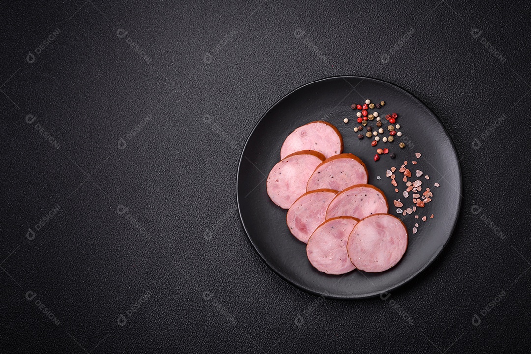 Deliciosa salsicha defumada com sal e especiarias cortadas em fatias sobre um fundo escuro de concreto