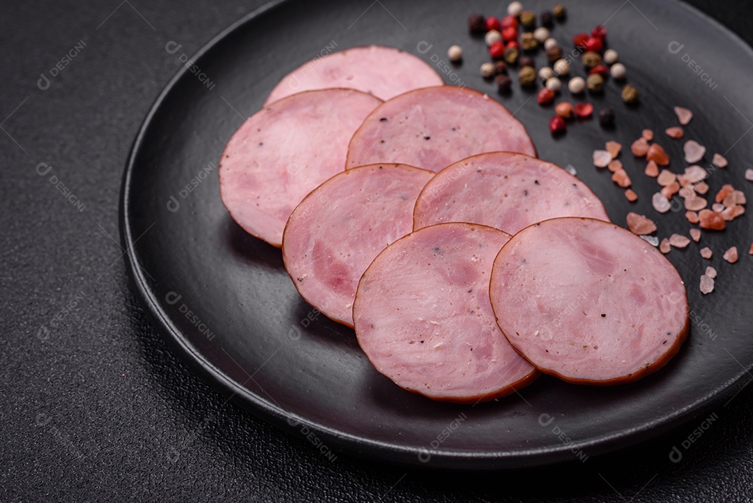Deliciosa salsicha defumada com sal e especiarias cortadas em fatias sobre um fundo escuro de concreto