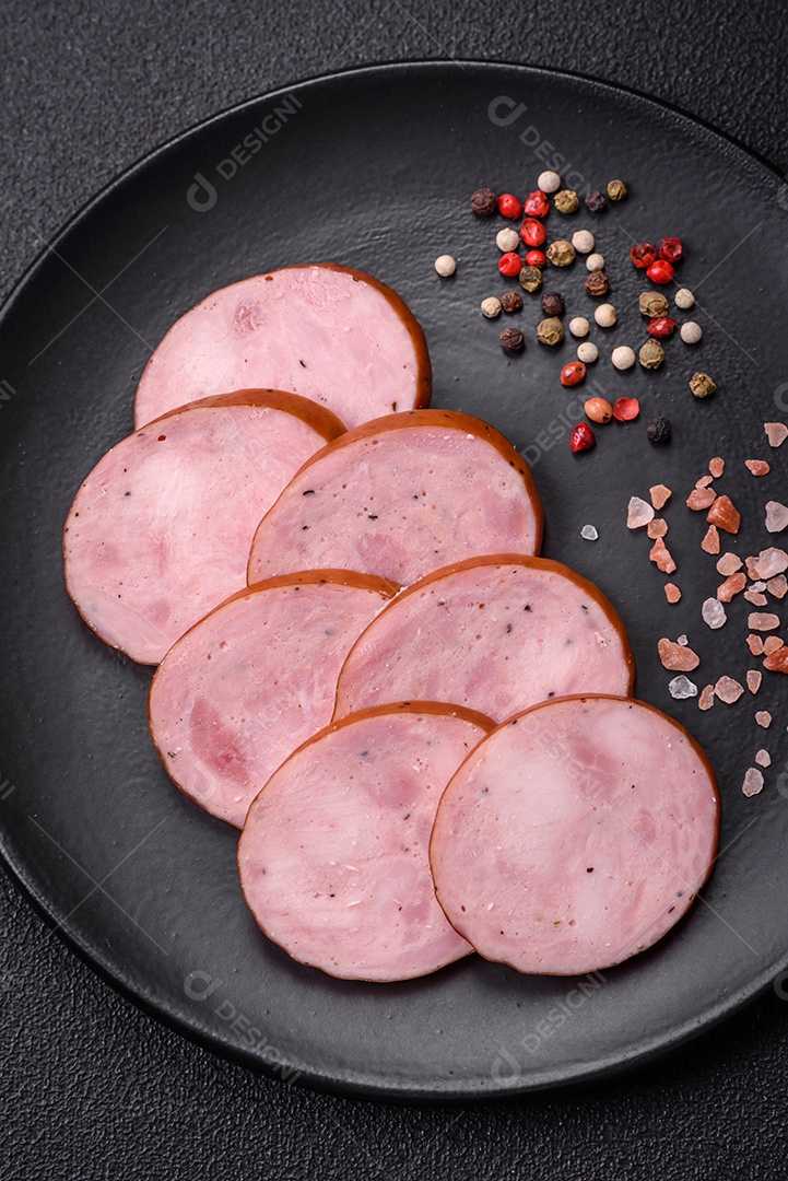 Deliciosa salsicha defumada com sal e especiarias cortadas em fatias sobre um fundo escuro de concreto