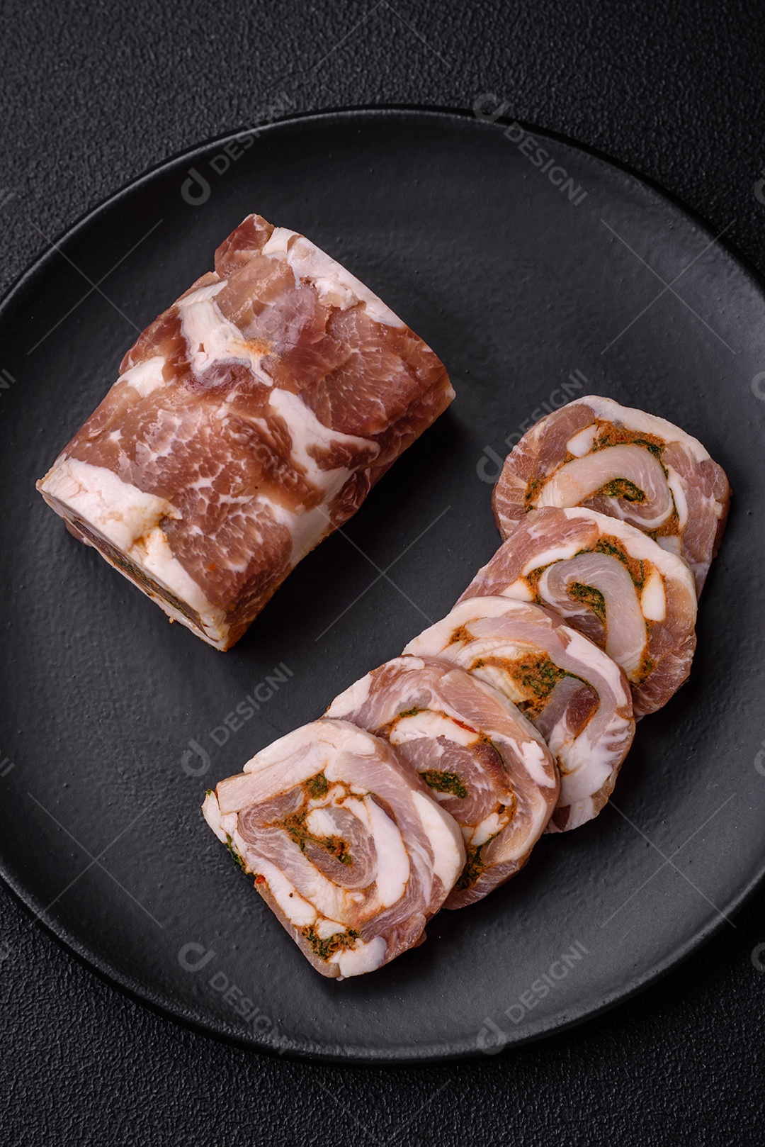 Bolo de carne delicioso com banha, sal, especiarias e ervas cortadas em fatias sobre um fundo escuro de concreto