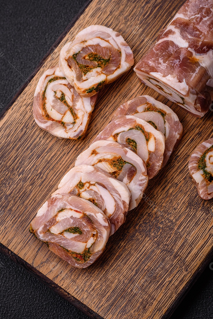 Bolo de carne delicioso com banha, sal, especiarias e ervas cortadas em fatias sobre um fundo escuro de concreto
